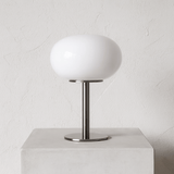 Table lamp with white shade and metal base on a light gray background