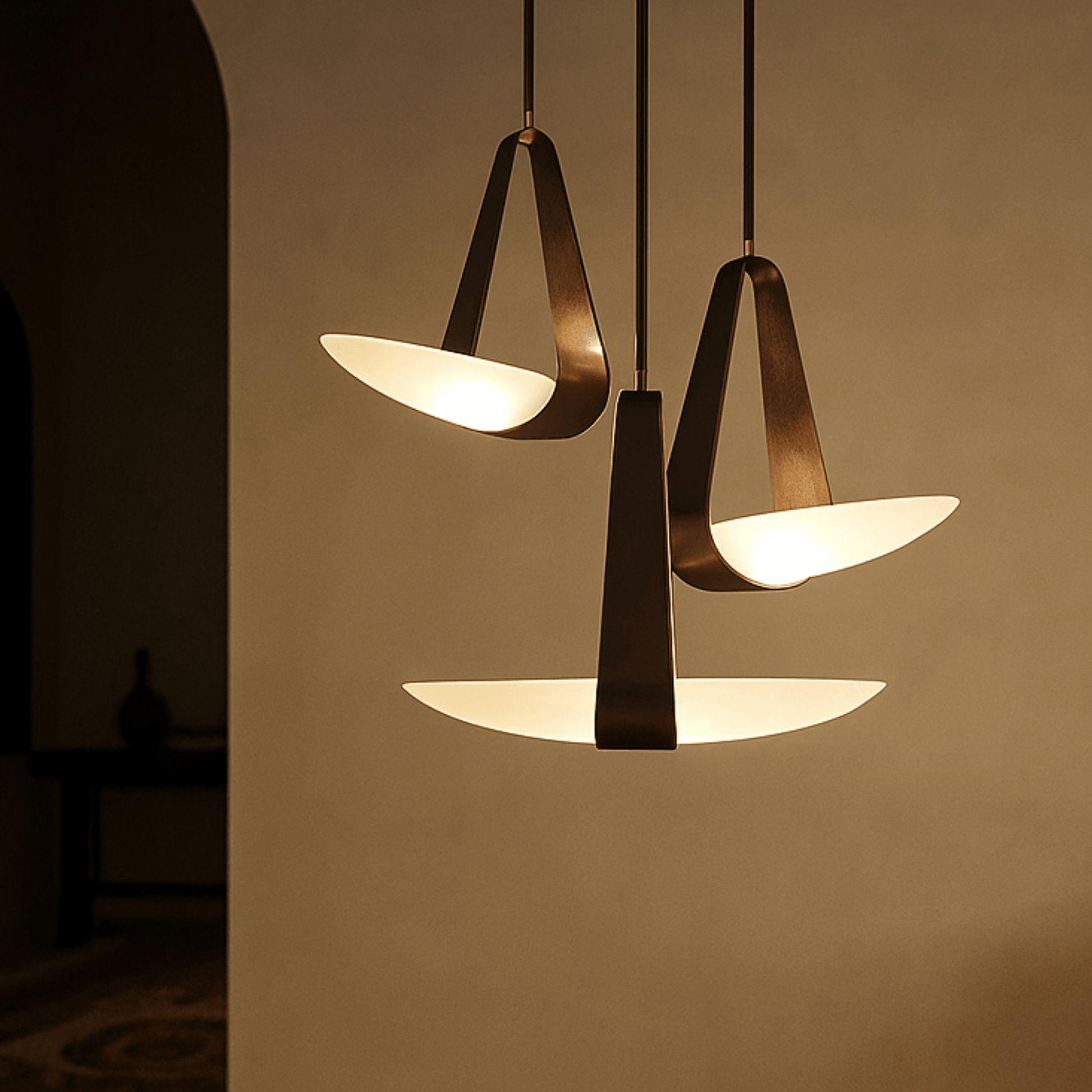 Modern pendant light fixture with three hanging lampshades on a neutral background