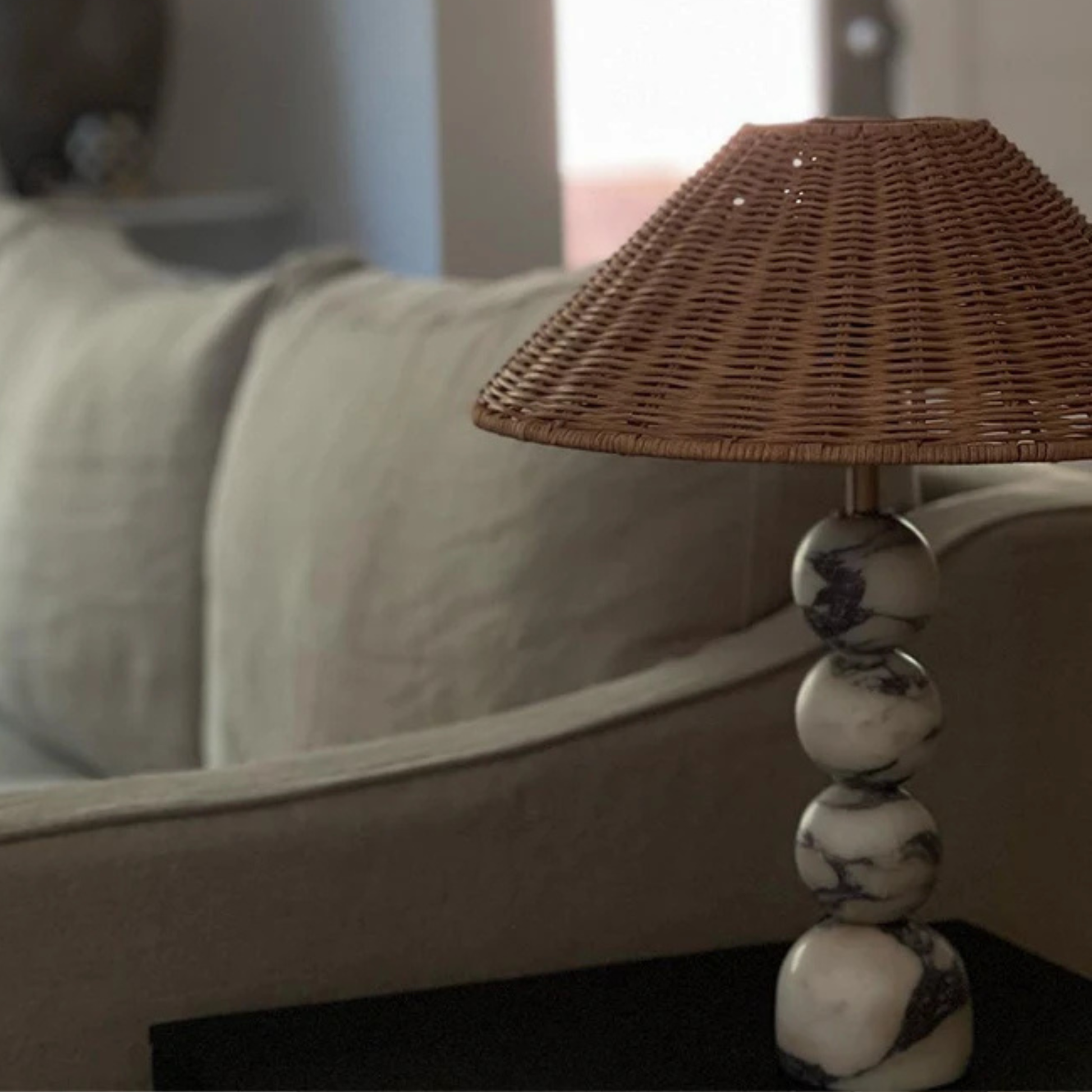 Lamp placed near a window on a stack of books, with natural light and plants in the background, giving a rustic homey vibe.