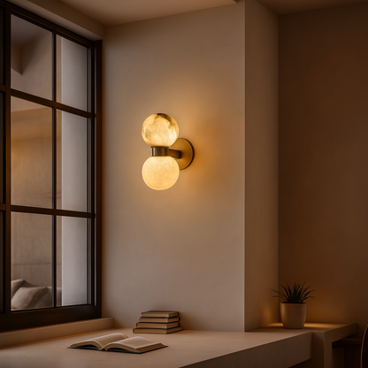 Wall sconce with two lights in a room with an open book and a plant.