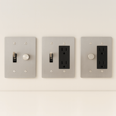 Three light switch and outlet covers on a white wall.