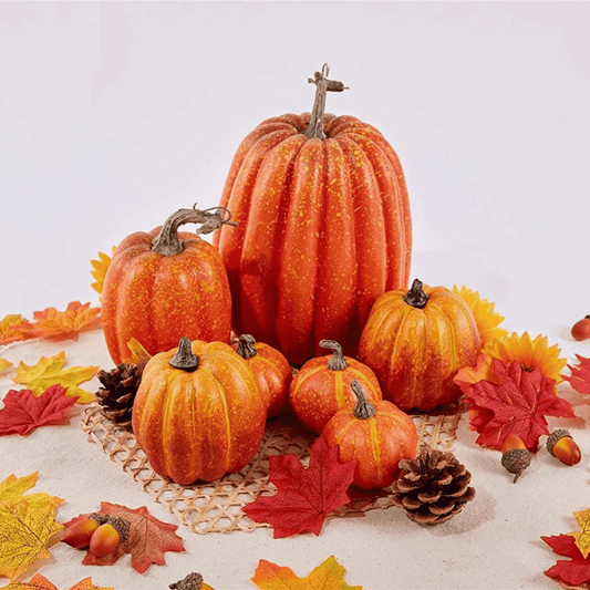 Decorative pumpkins with autumn leaves and pinecones on a light background