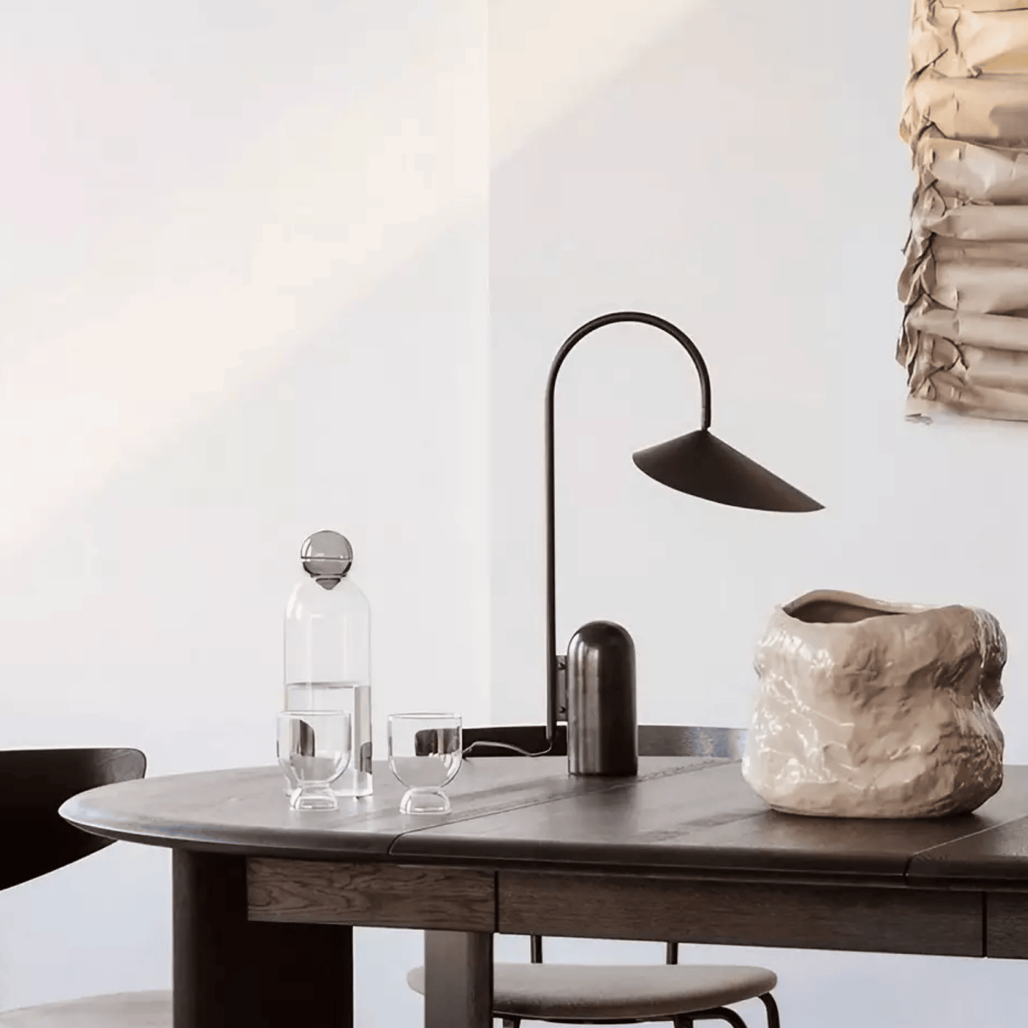 Modern interior with a table, lamp, and decorative items against a white wall.