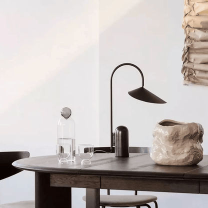 Modern interior with a table, lamp, and decorative items against a white wall.