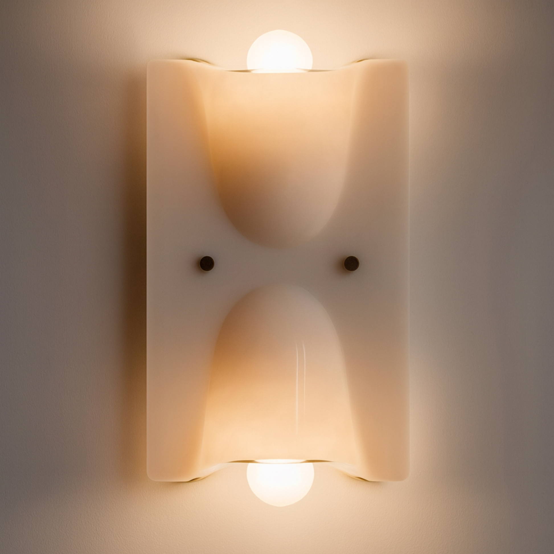 Wall-mounted light fixture with two illuminated bulbs on a neutral background