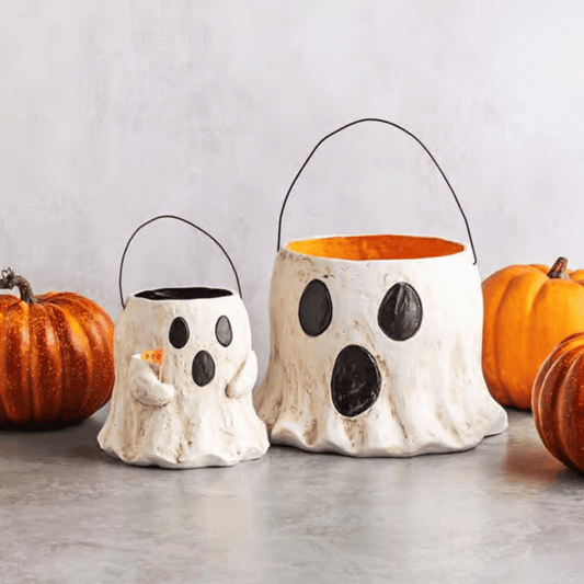 Two ghost-shaped Halloween buckets with pumpkins on a light background