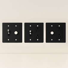 Three black wall plates with different electrical symbols on a beige background