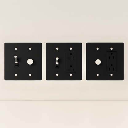 Three black wall plates with different electrical symbols on a beige background