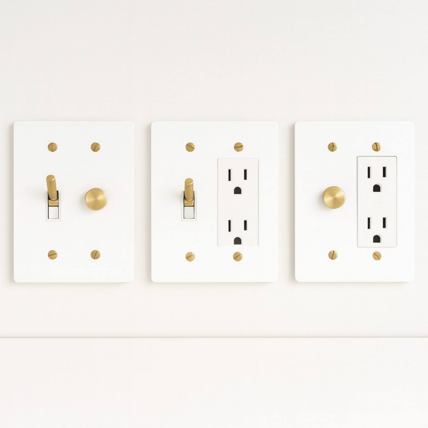 Three white light switch and outlet covers with gold accents on a white background