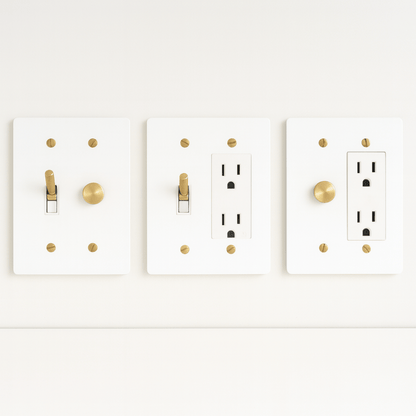 Three white light switch and outlet covers with gold accents on a white background