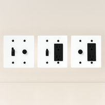 Three white wall plate covers with black outlets on a beige background