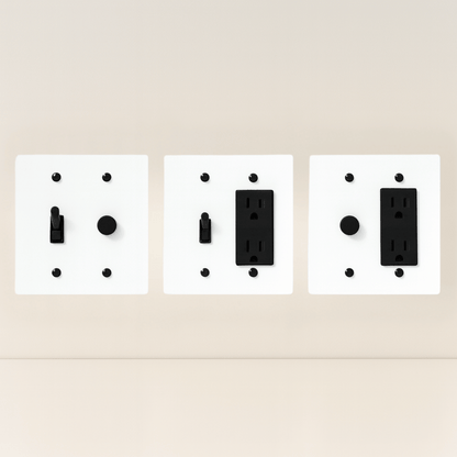 Three white wall plate covers with black outlets on a beige background