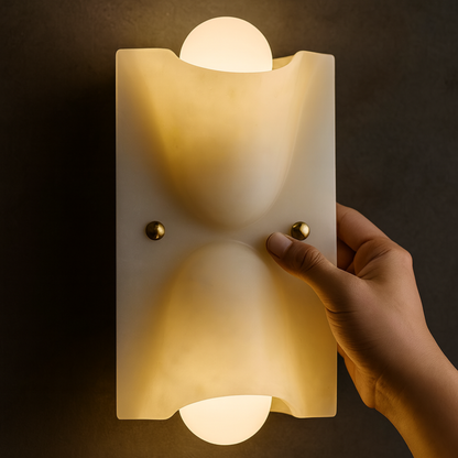 Hand holding a modern wall light fixture against a dark background