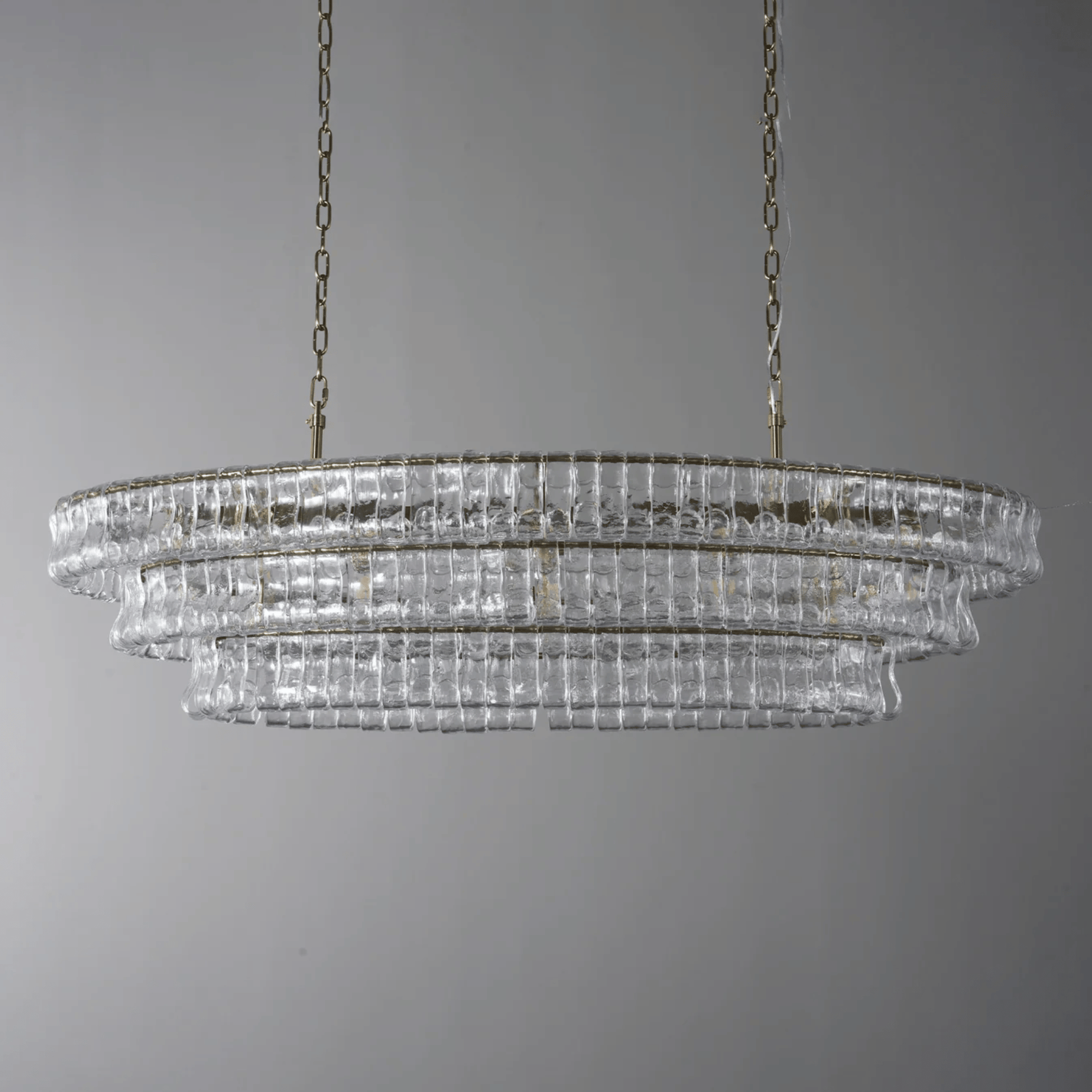 Chandelier with clear glass and gold metal frame on a gray background