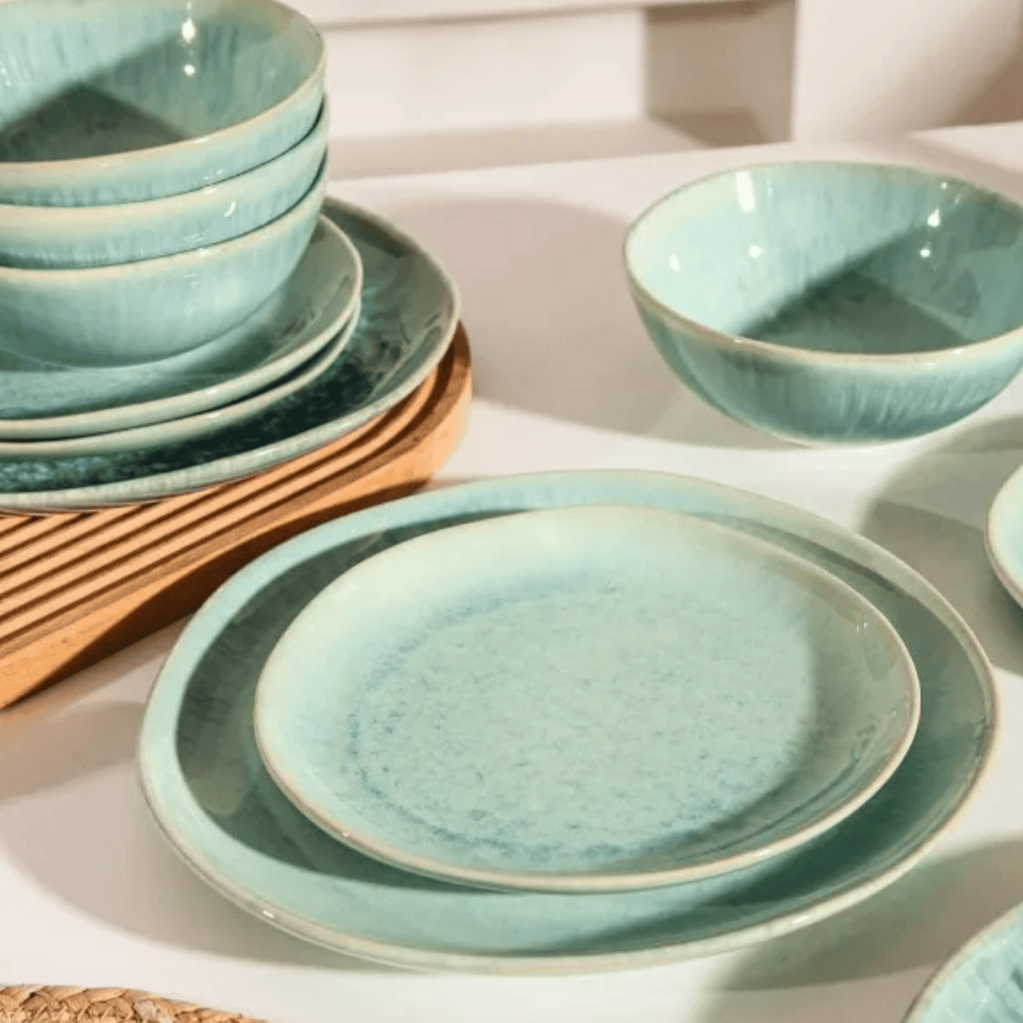 Set of teal ceramic plates and bowls on a white surface