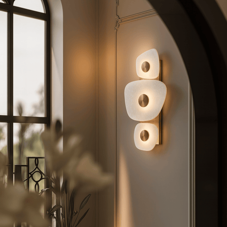 Modern wall sconce with three round lights on a neutral wall.