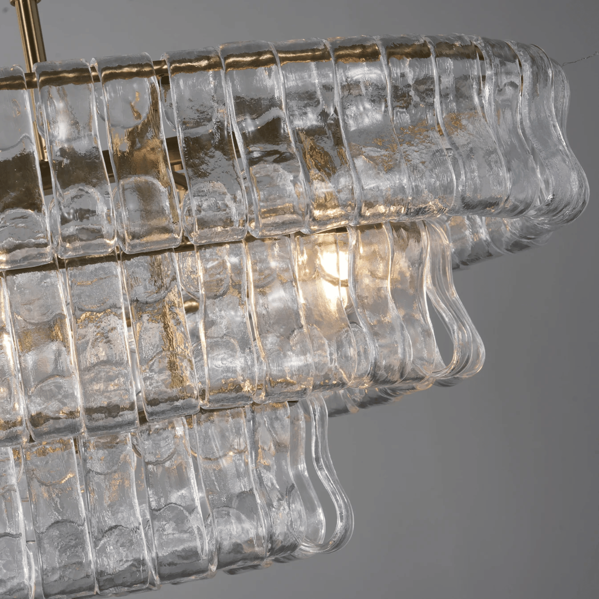 Close-up of a chandelier with clear glass and gold accents on a gray background