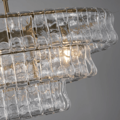 Close-up of a chandelier with clear glass and gold accents on a gray background