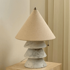 Table lamp with a cone-shaped beige lampshade and marble base on a wooden surface.