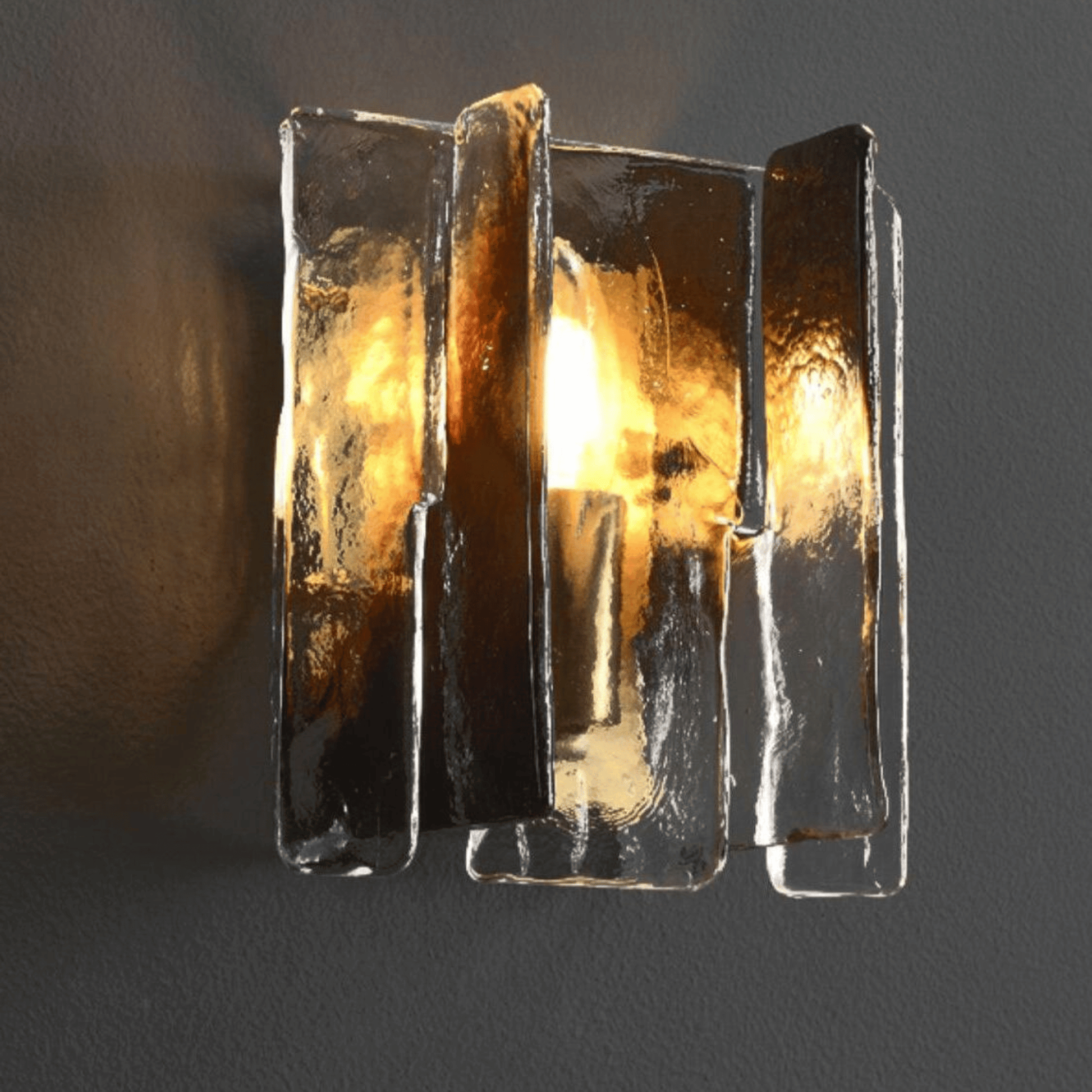 Decorative wall light fixture with glass panels on a dark background