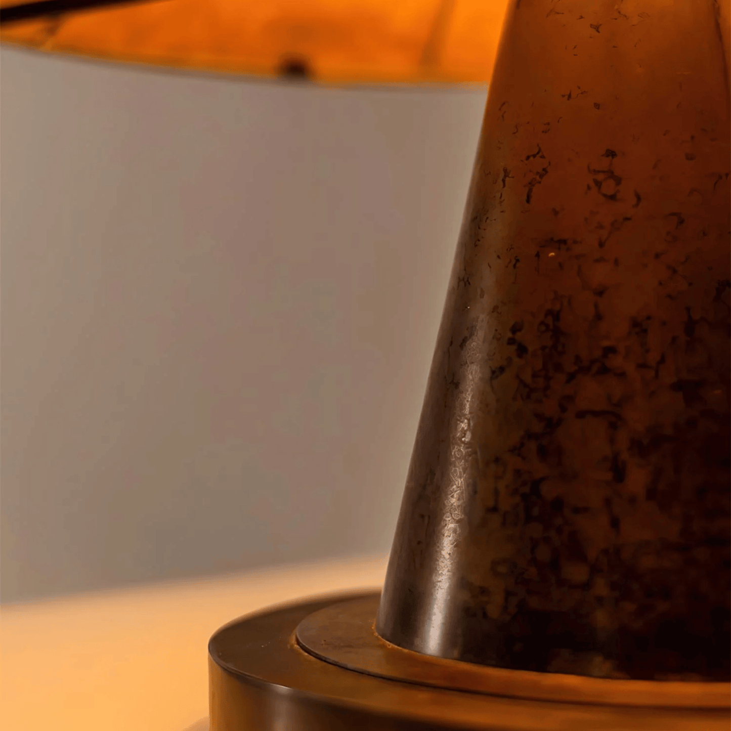 Close-up of a textured brown lampshade on a wooden base with a blurred background.