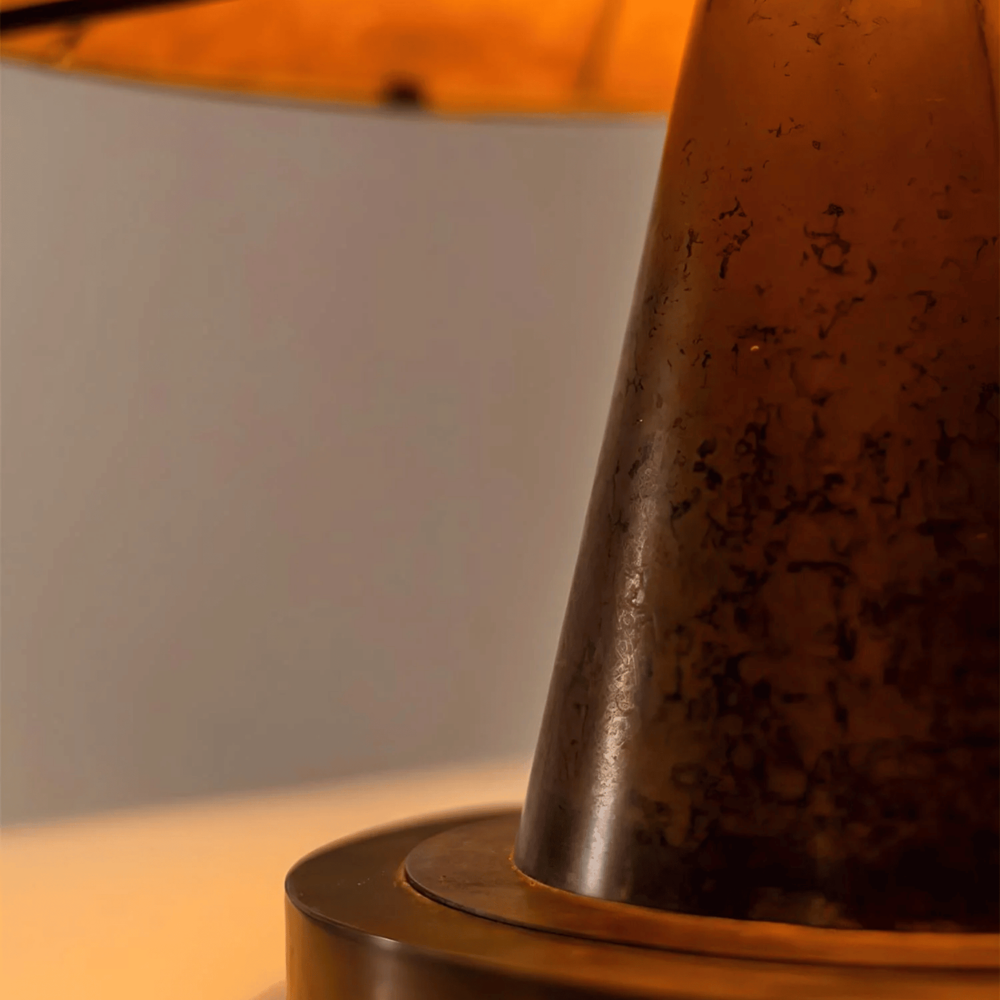 Close-up of a textured brown lampshade on a wooden base with a blurred background.