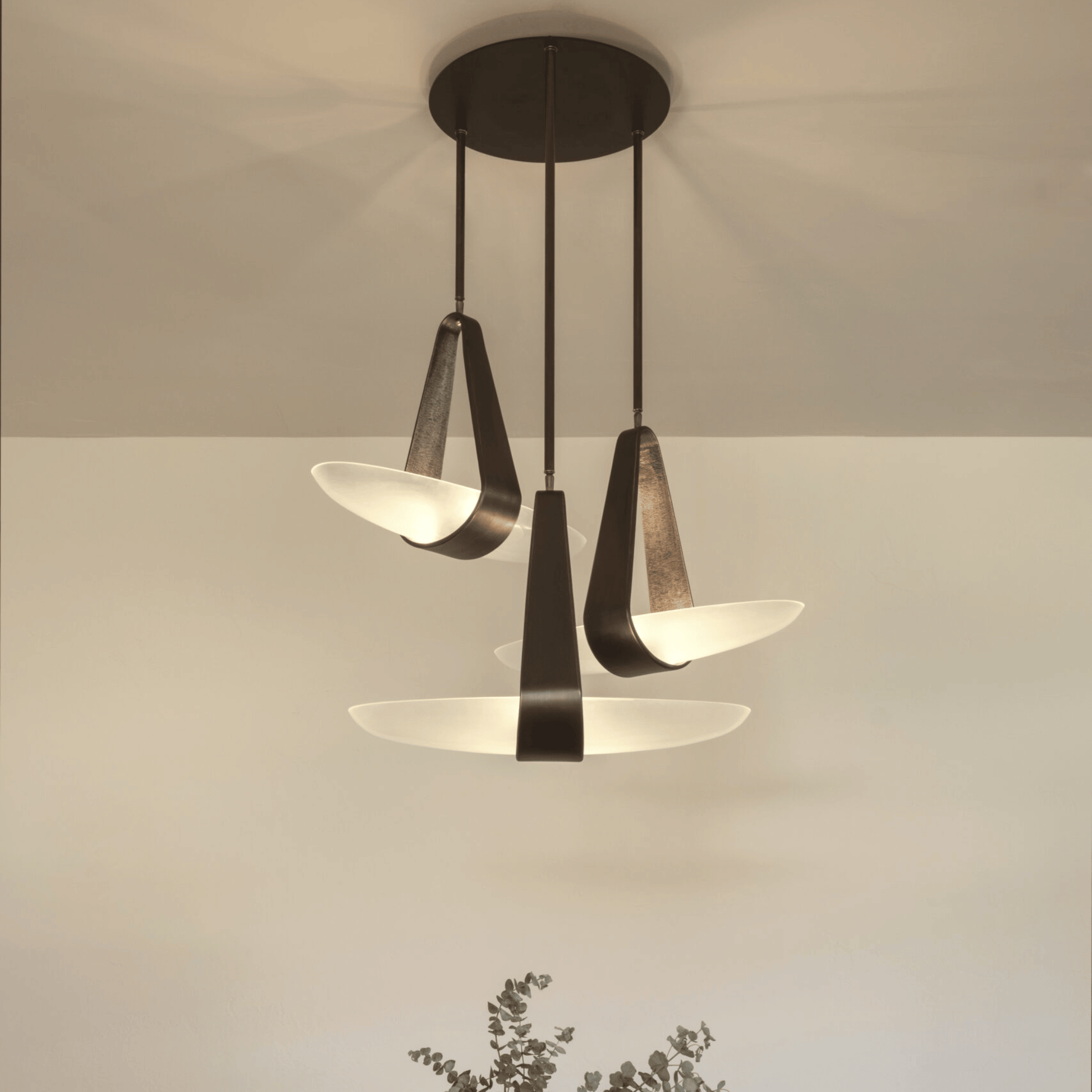 Modern pendant light fixture with three glass shades on a neutral background