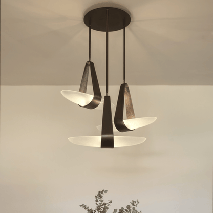 Modern pendant light fixture with three glass shades on a neutral background