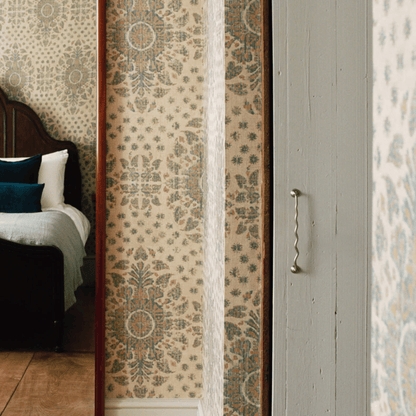 Patterned wallpaper with a wooden door and bed in the background