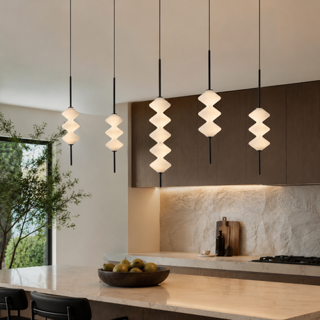 Modern kitchen with pendant lights and a bowl of fruit on the counter.