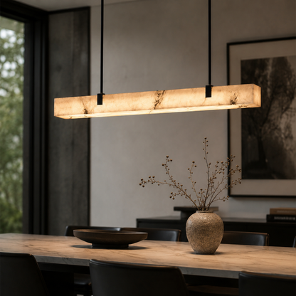 Modern pendant light over a dining table with a vase of branches.