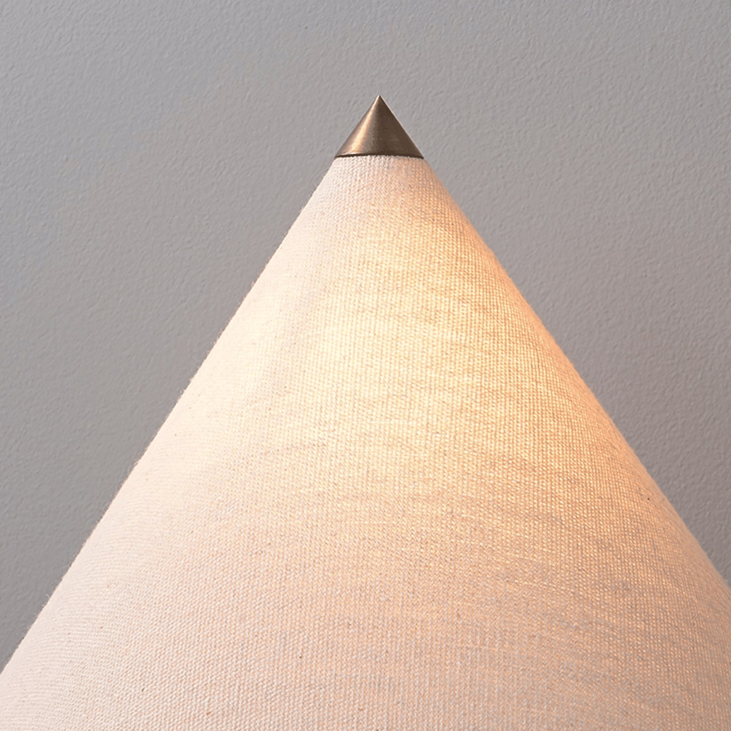 Conical lamp with a metallic top on a plain background