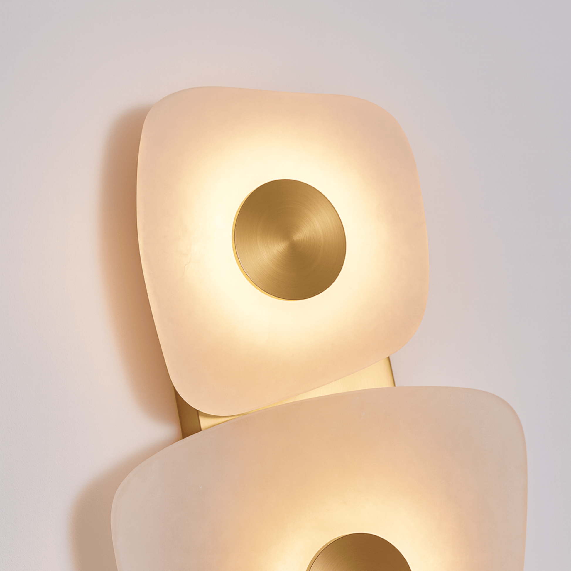 Modern wall lamp with a gold circular accent on a light gray background