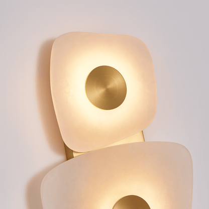 Modern wall lamp with a gold circular accent on a light gray background