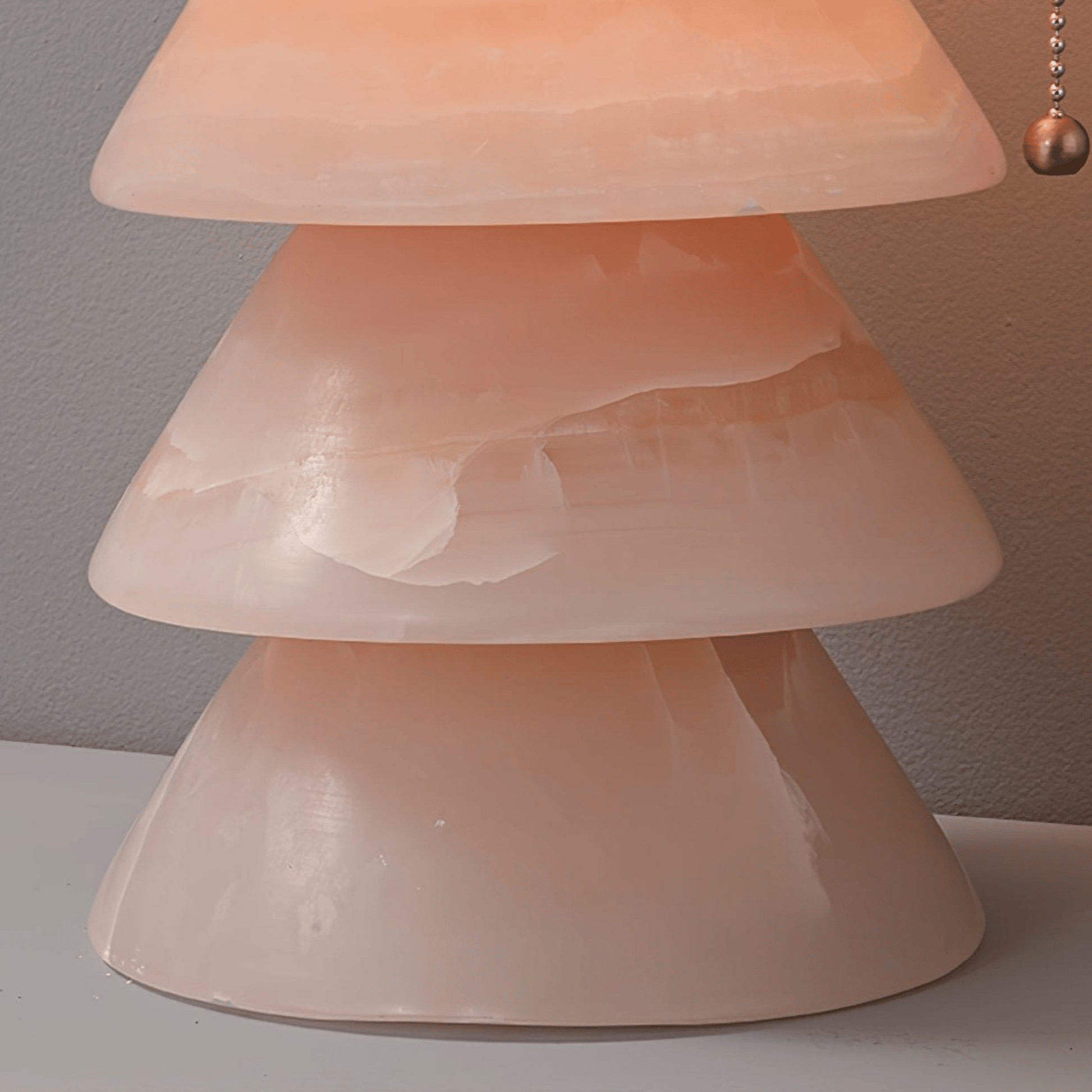 Close-up of a pink lamp with a textured shade on a neutral background