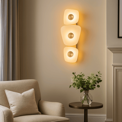 Modern wall sconce with a beige armchair and a small table with a vase of flowers in a room.