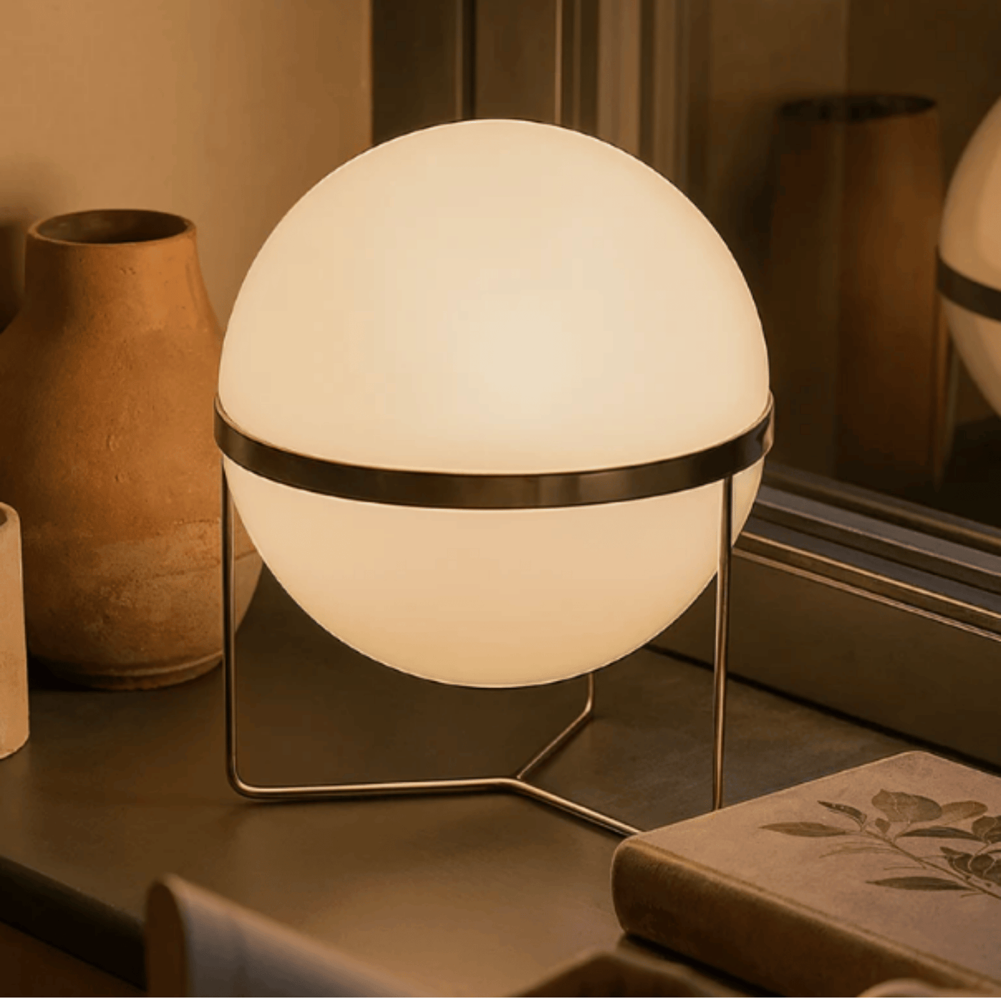 Spherical table lamp with a warm glow on a surface with decorative items.