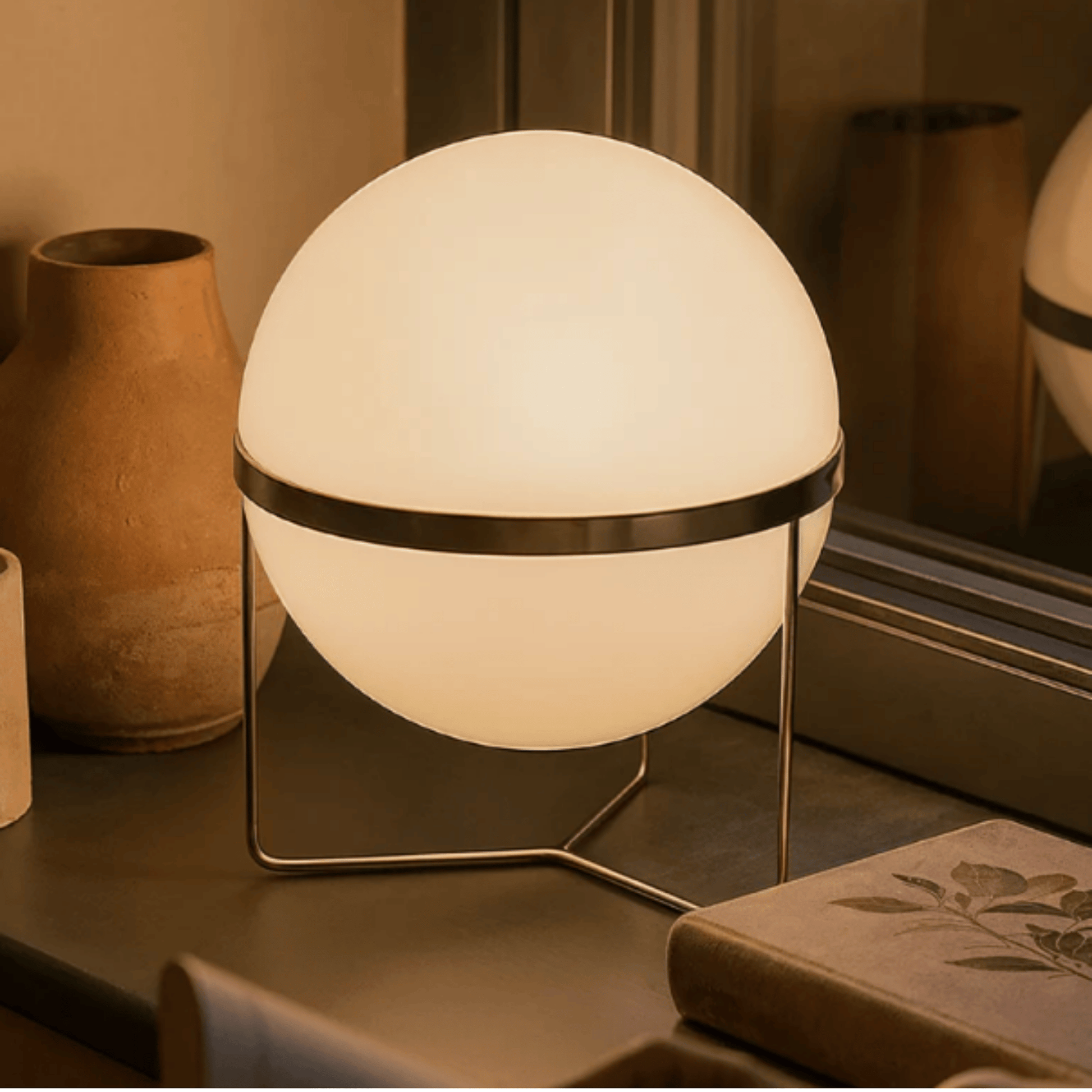 Spherical table lamp with a warm glow on a surface with decorative items.