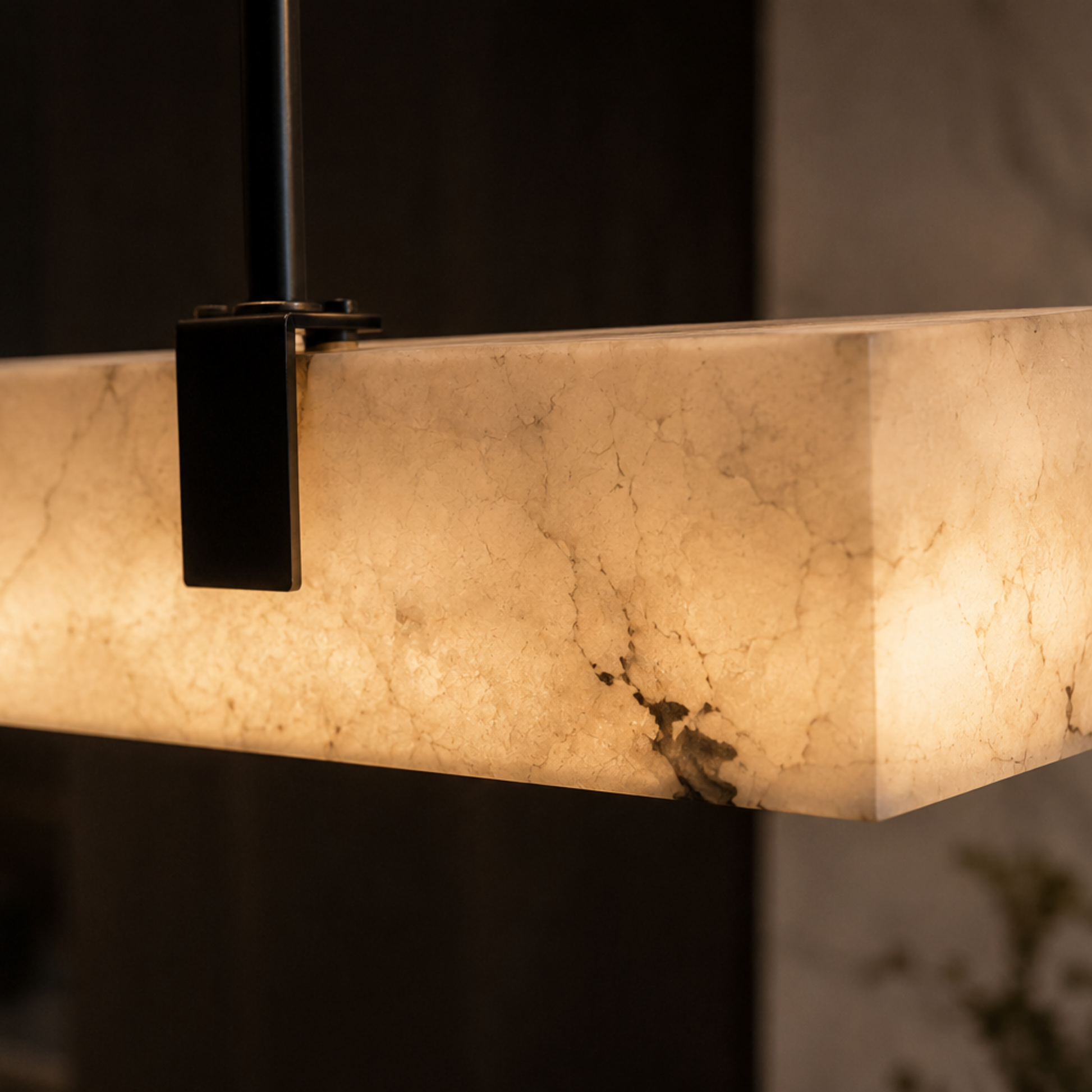 Marble-patterned light fixture with black metal bracket on a dark background