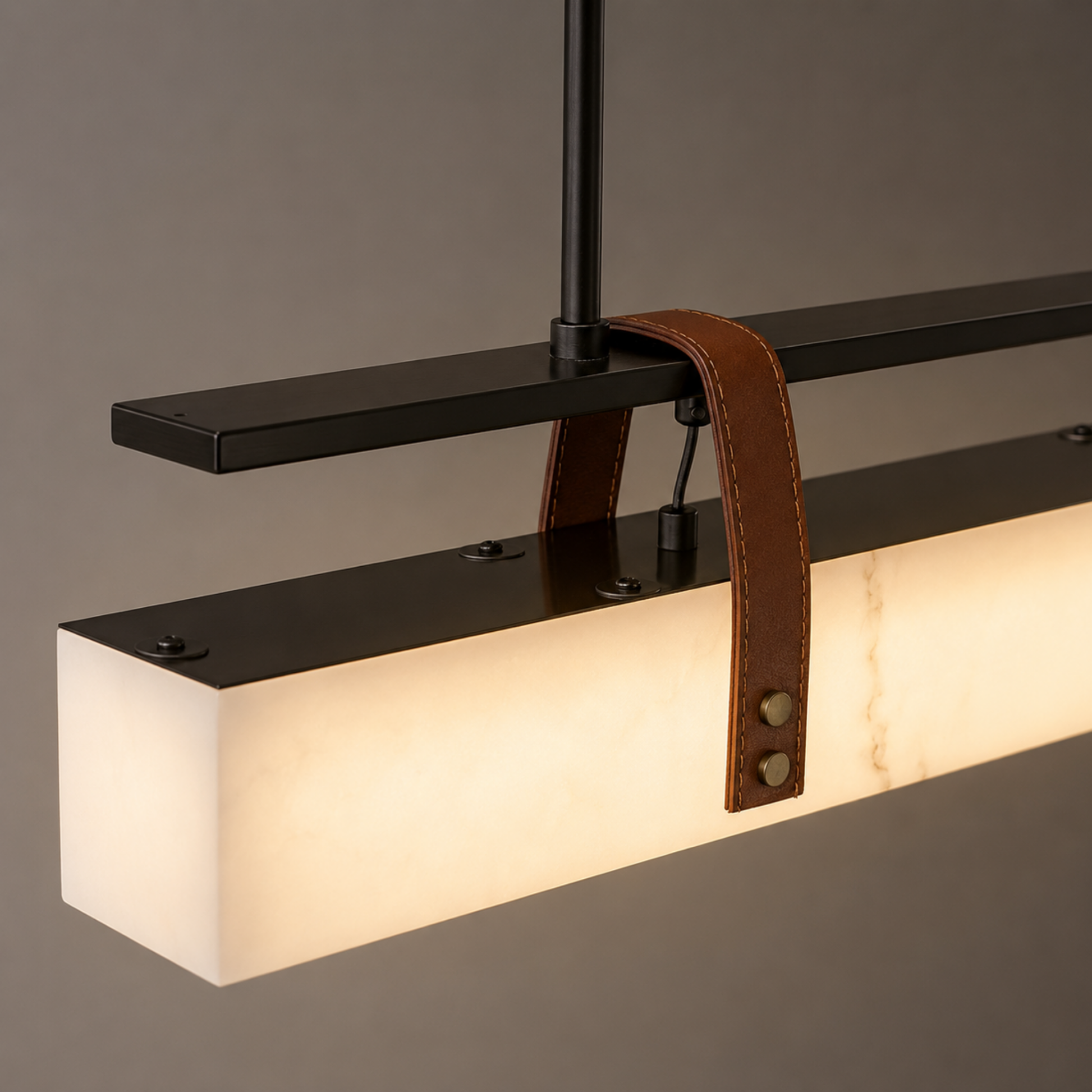 Modern pendant light with black frame, white glass shade, and brown leather strap on a gray background.