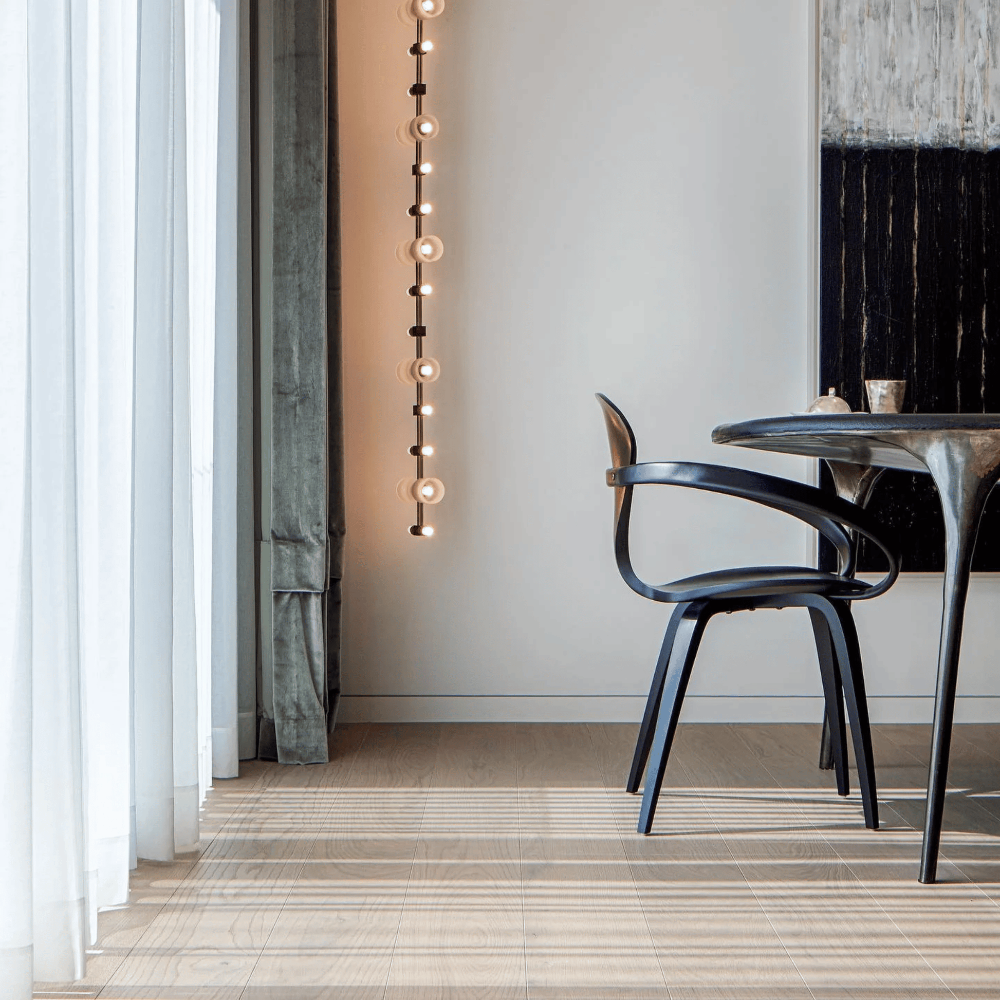 Modern interior with a black chair and table near a wall with hanging lights.