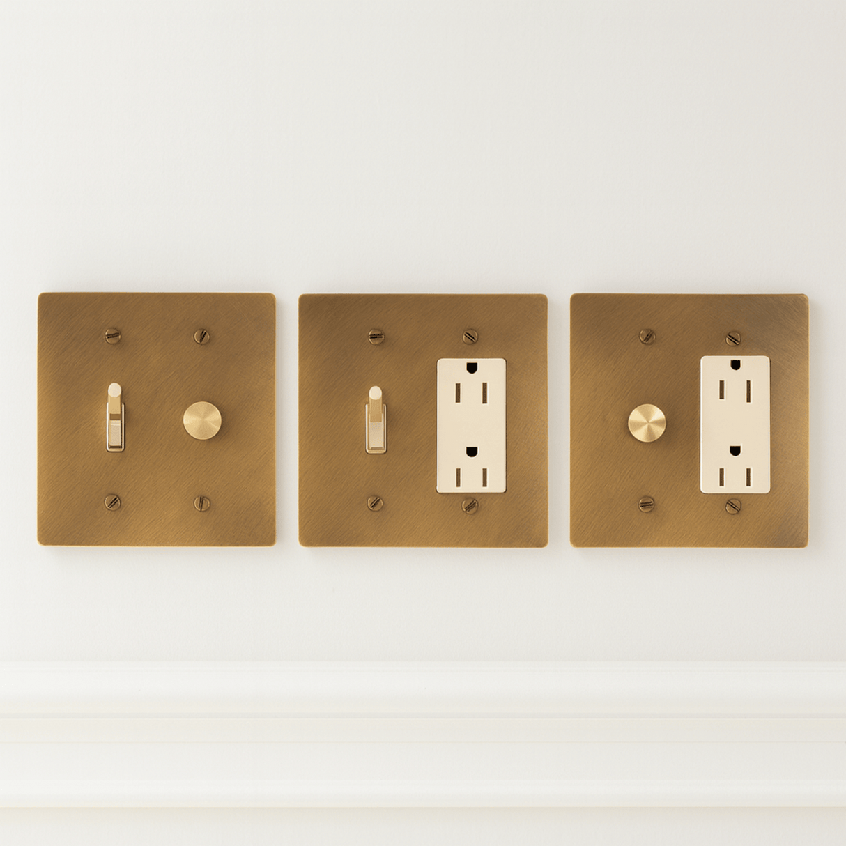 Three brass light switch and outlet covers on a white background