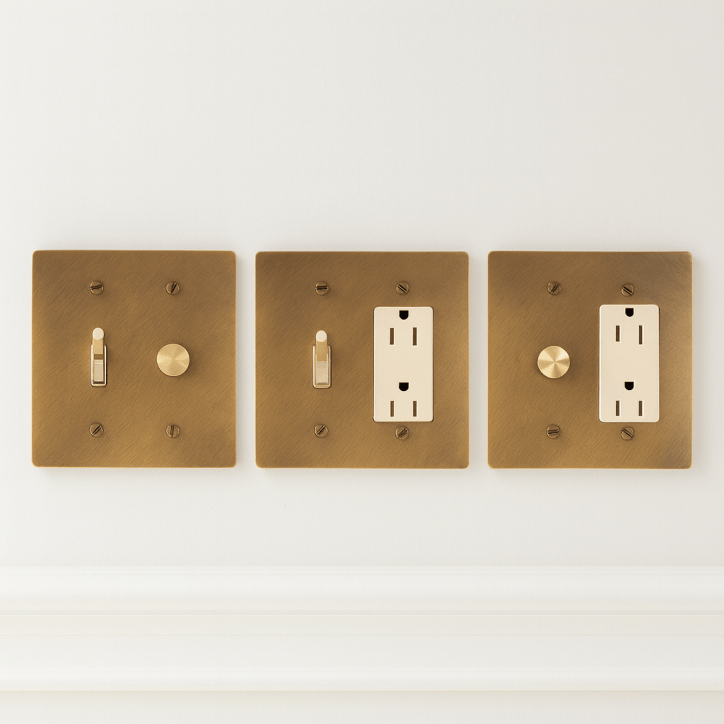 Three brass light switch and outlet covers on a white background