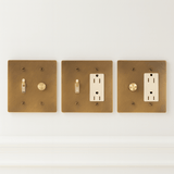 Three brass light switch and outlet covers on a white background