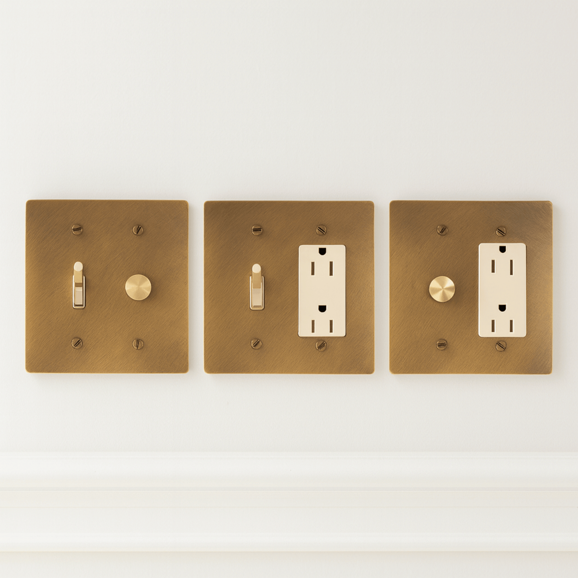 Three brass light switch and outlet covers on a white background