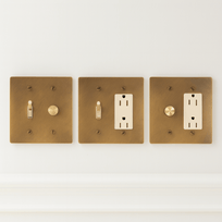 Three brass light switch and outlet covers on a white background