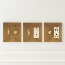 Three brass light switch and outlet covers on a white background