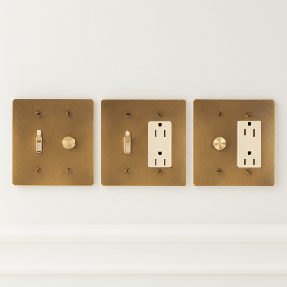 Three brass light switch and outlet covers on a white background