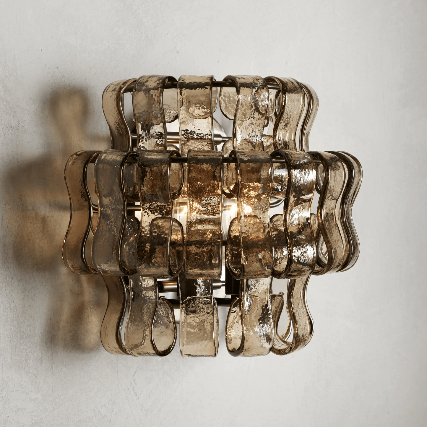 Decorative wall light fixture with wavy glass design on a plain background