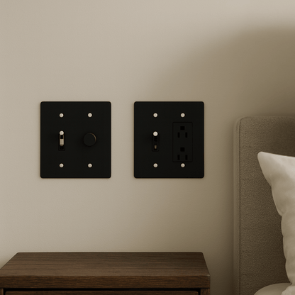 Black light switch and outlet covers on a beige wall next to a wooden nightstand.